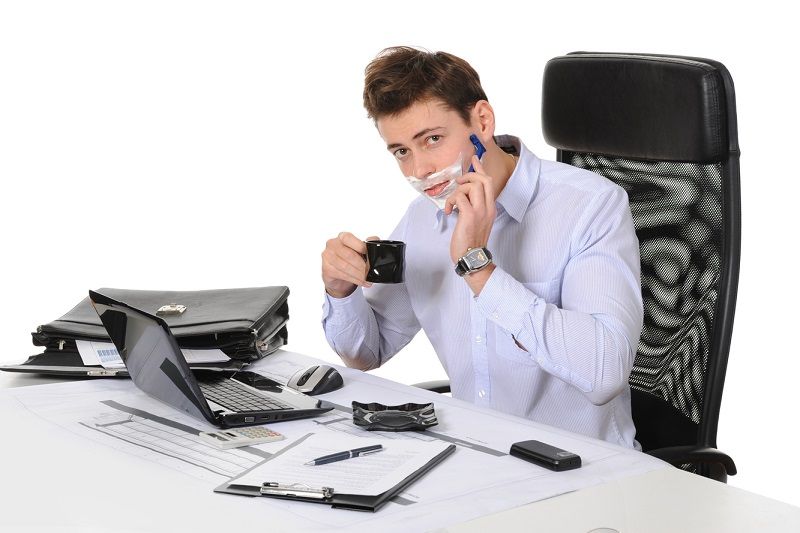 Man shaving at computer while he works